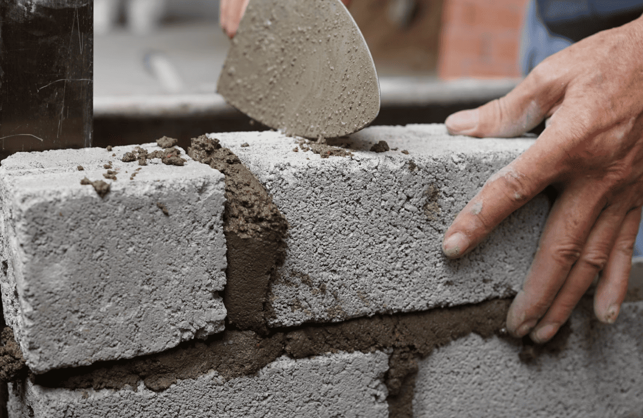 Stone Haven Developments A person is laying cement blocks, applying mortar with a trowel to build a wall. Ontario