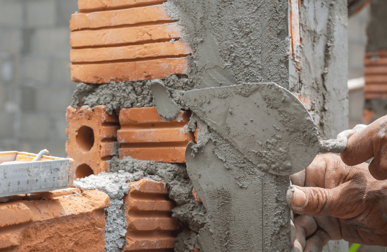 Stone Haven Developments A person applies cement mortar to a brick wall with a trowel during a construction process. Ontario