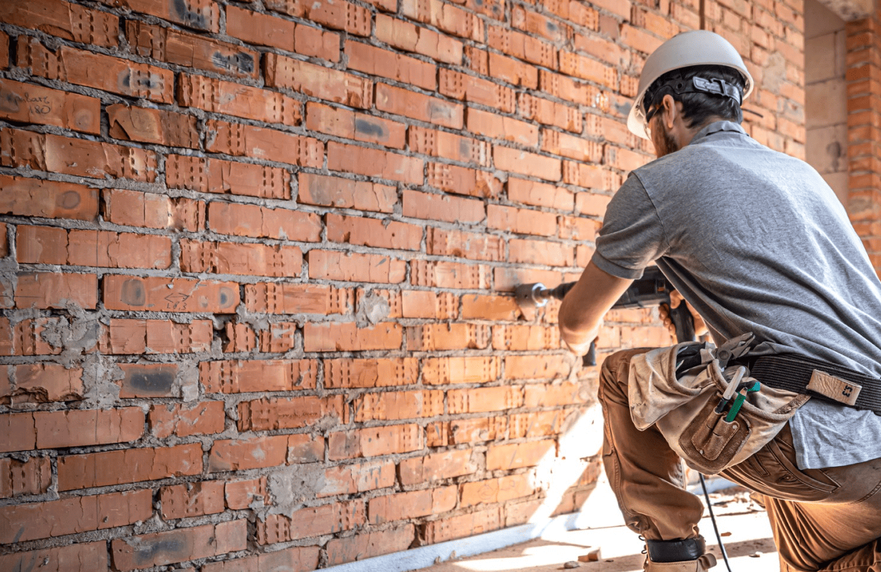 Stone Haven Developments A construction worker in a hard hat uses a power drill on a brick wall at a building site. Ontario
