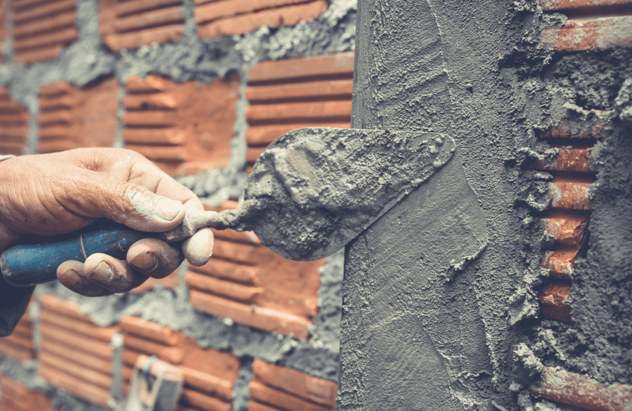 Stone Haven Developments A hand uses a trowel to spread cement onto a brick wall during construction. Ontario