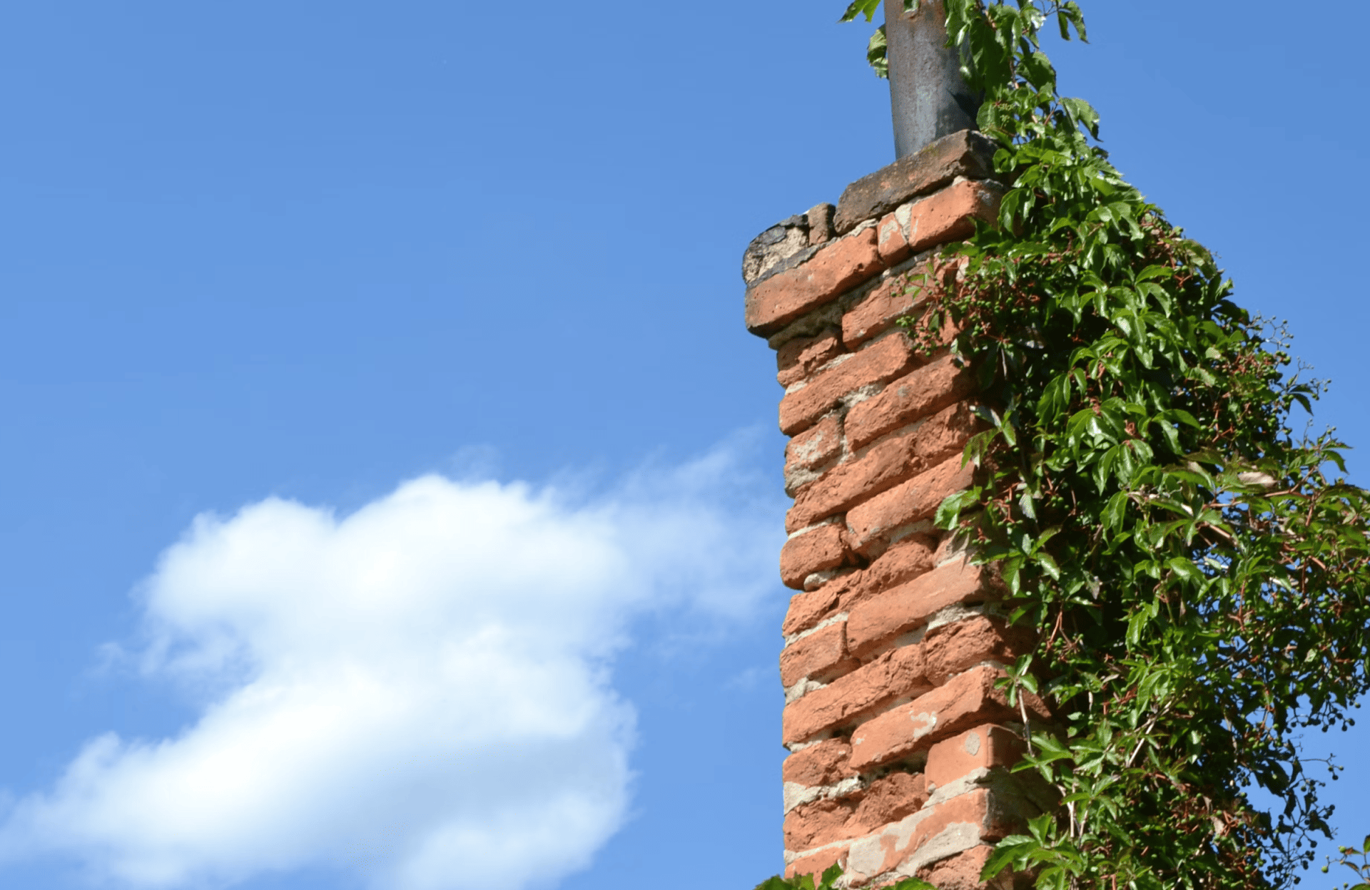 Stone Haven Developments A red brick chimney covered with green ivy stands against a blue sky with a few white clouds. Ontario