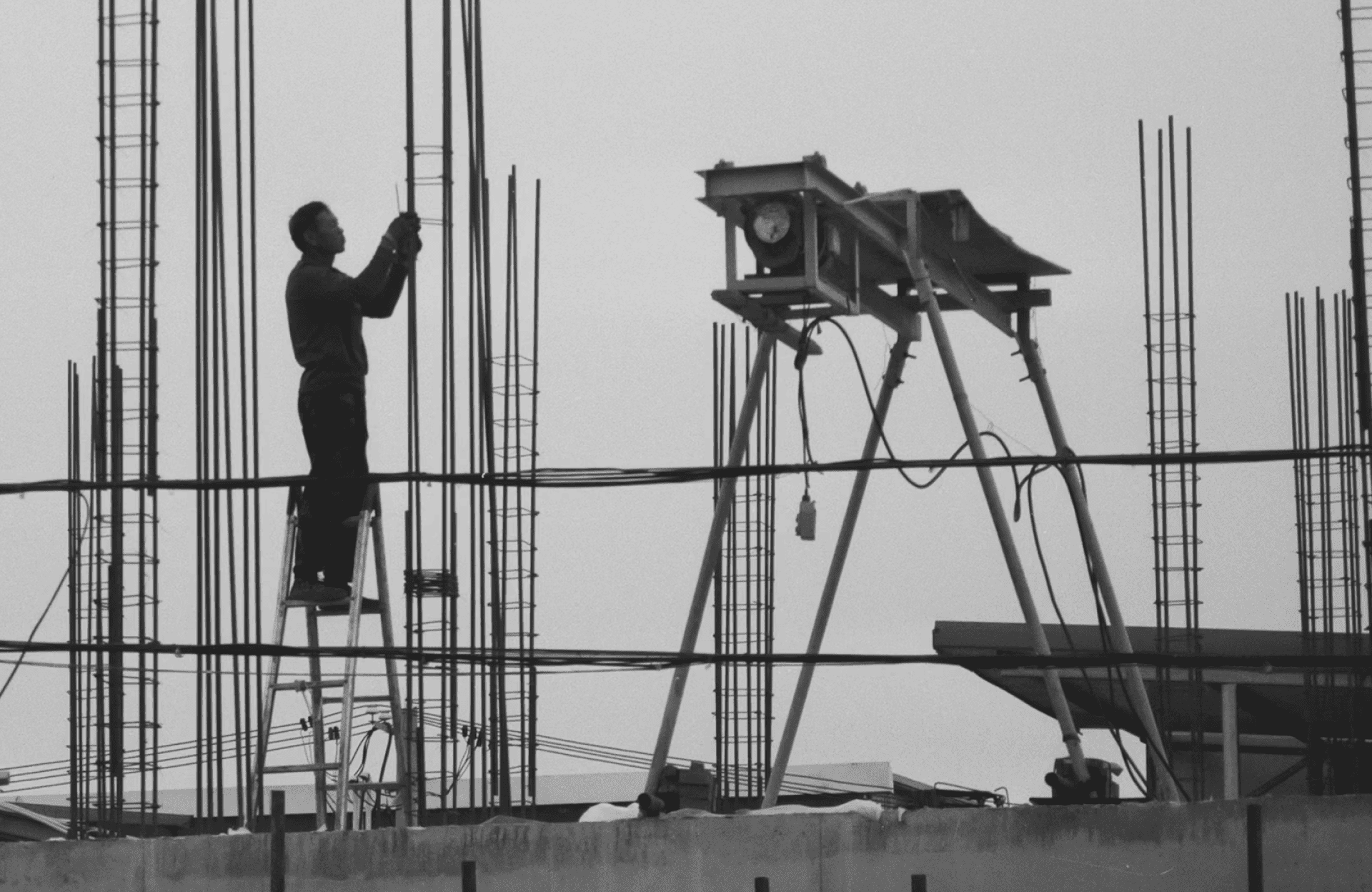 Stone Haven Developments A person stands on a ladder tying steel reinforcement rods at a construction site, with building materials and equipment visible in the background. Ontario