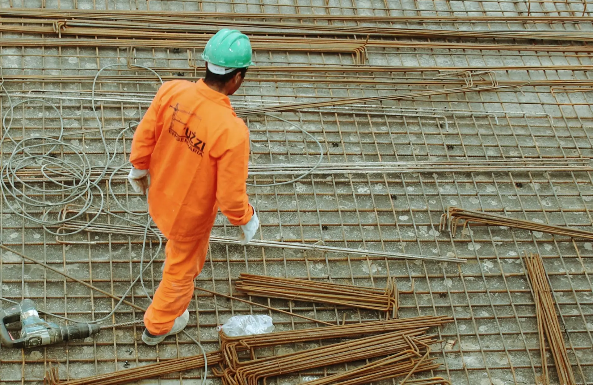 Stone Haven Developments A construction worker in an orange uniform and green helmet stands on a metal rebar grid, with rebar and tools scattered around. Ontario