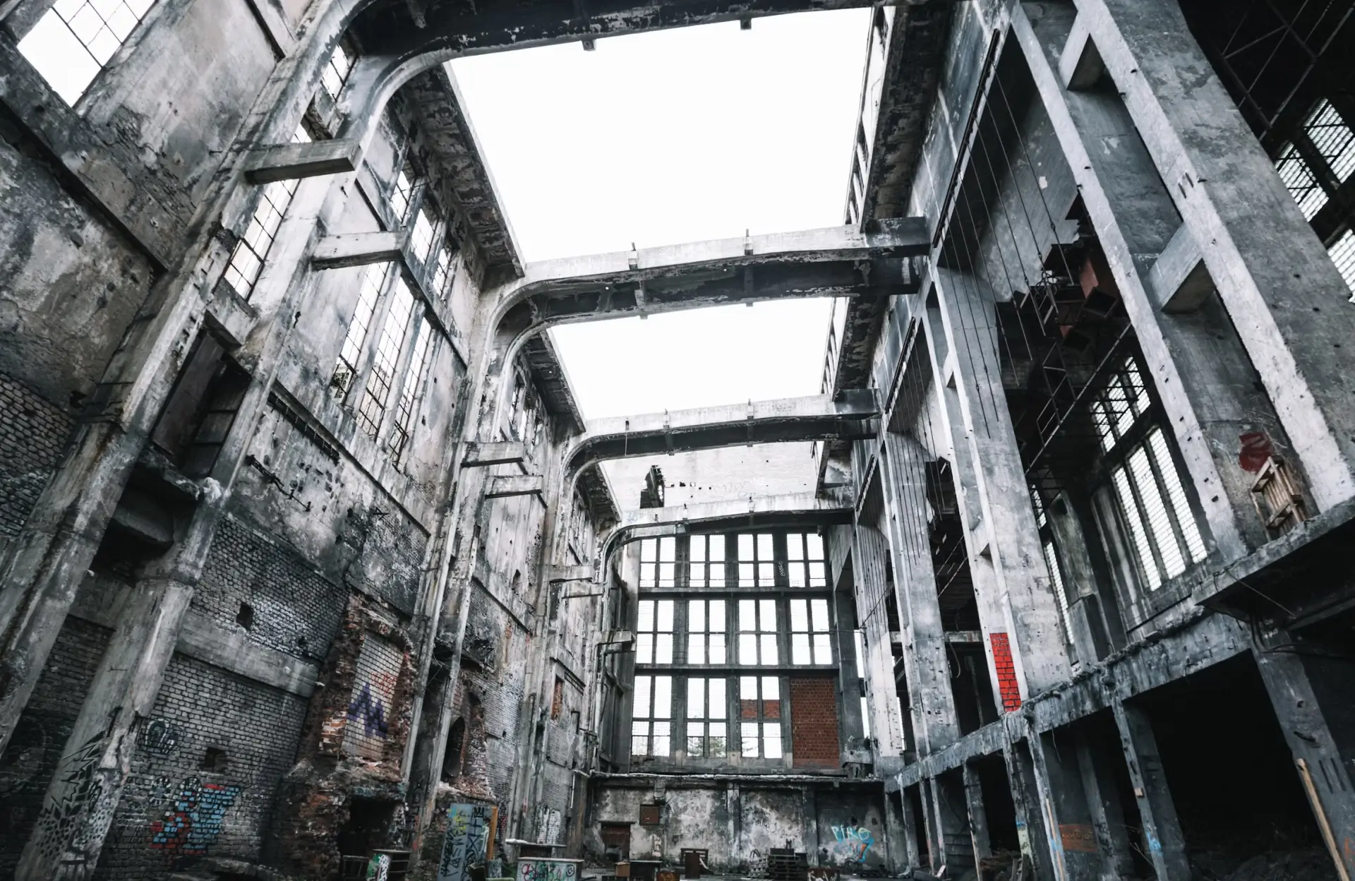Stone Haven Developments Interior of an abandoned industrial building with large broken windows, exposed beams, and deteriorating concrete walls, open to the sky above. Ontario