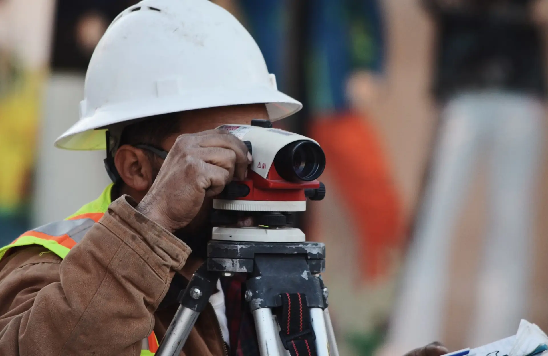Stone Haven Developments A construction worker in a white hard hat uses a surveying instrument mounted on a tripod at a worksite. Ontario
