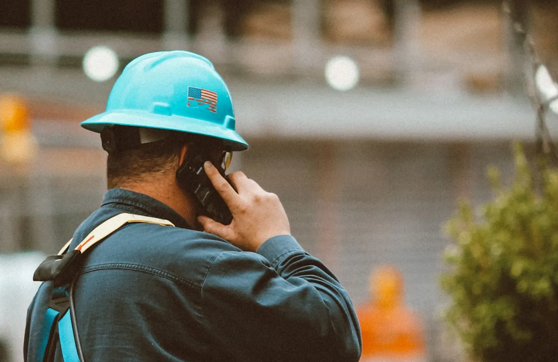 Stone Haven Developments A construction worker wearing a blue hard hat and safety harness talks on a cellphone at a worksite. Ontario