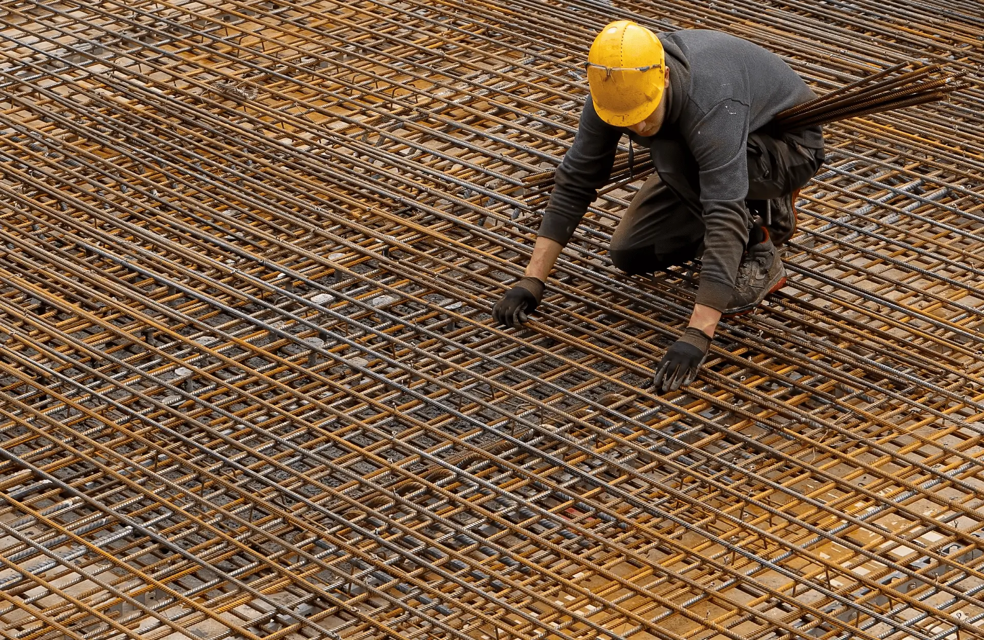Stone Haven Developments A construction worker in a yellow helmet arranges steel rebar on a construction site, preparing for a concrete pour. Ontario