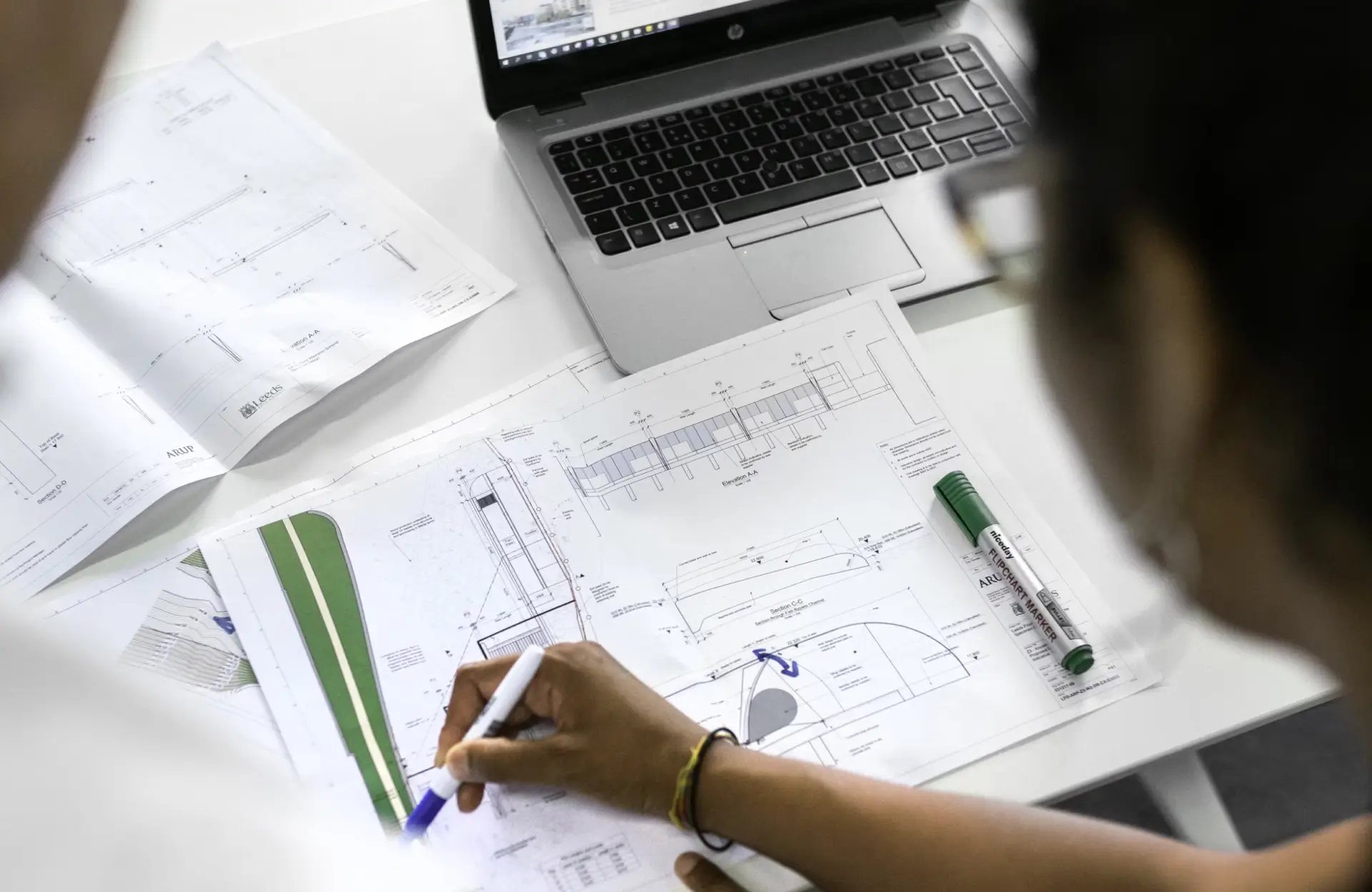 Stone Haven Developments Two people review and mark up architectural blueprints with pens at a desk, with a laptop and additional plans visible nearby. Ontario
