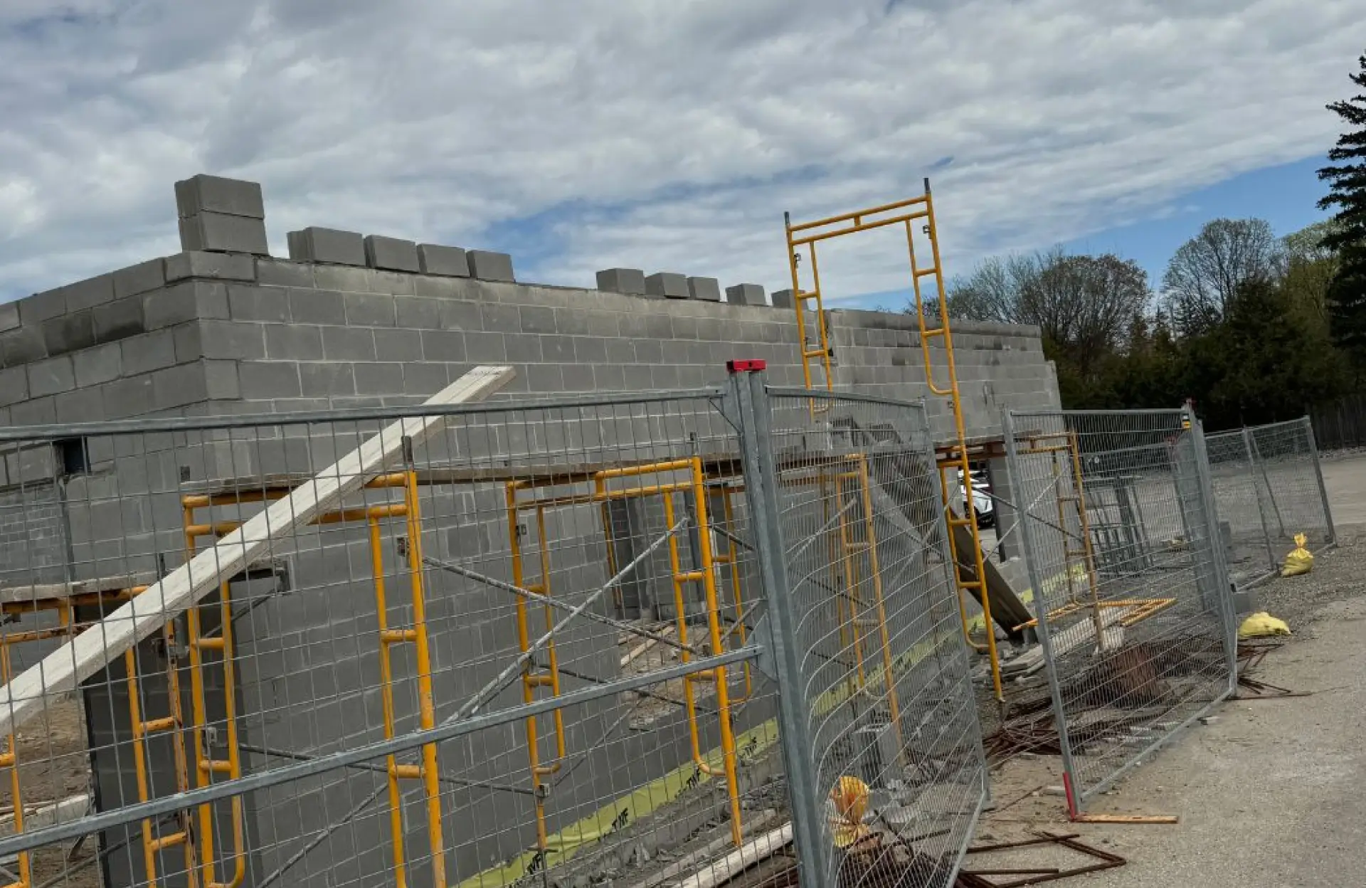 Stone Haven Developments Partially constructed gray concrete block building with scaffolding and fencing in front, under a cloudy sky. Ontario