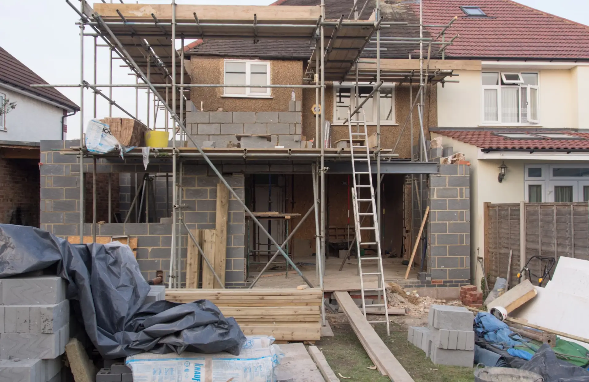 Stone Haven Developments A two-story house under construction with scaffolding, exposed brickwork, building materials, and tools scattered in the yard. Ontario