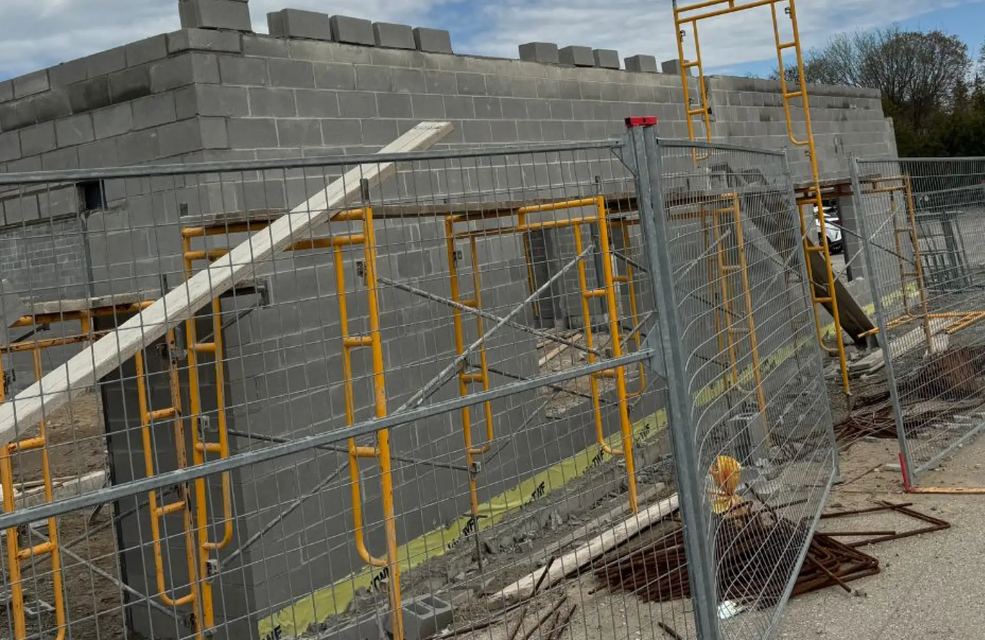 Stone Haven Developments A partially constructed concrete block building is surrounded by metal fencing and scaffolding, with construction materials scattered on the ground. Ontario