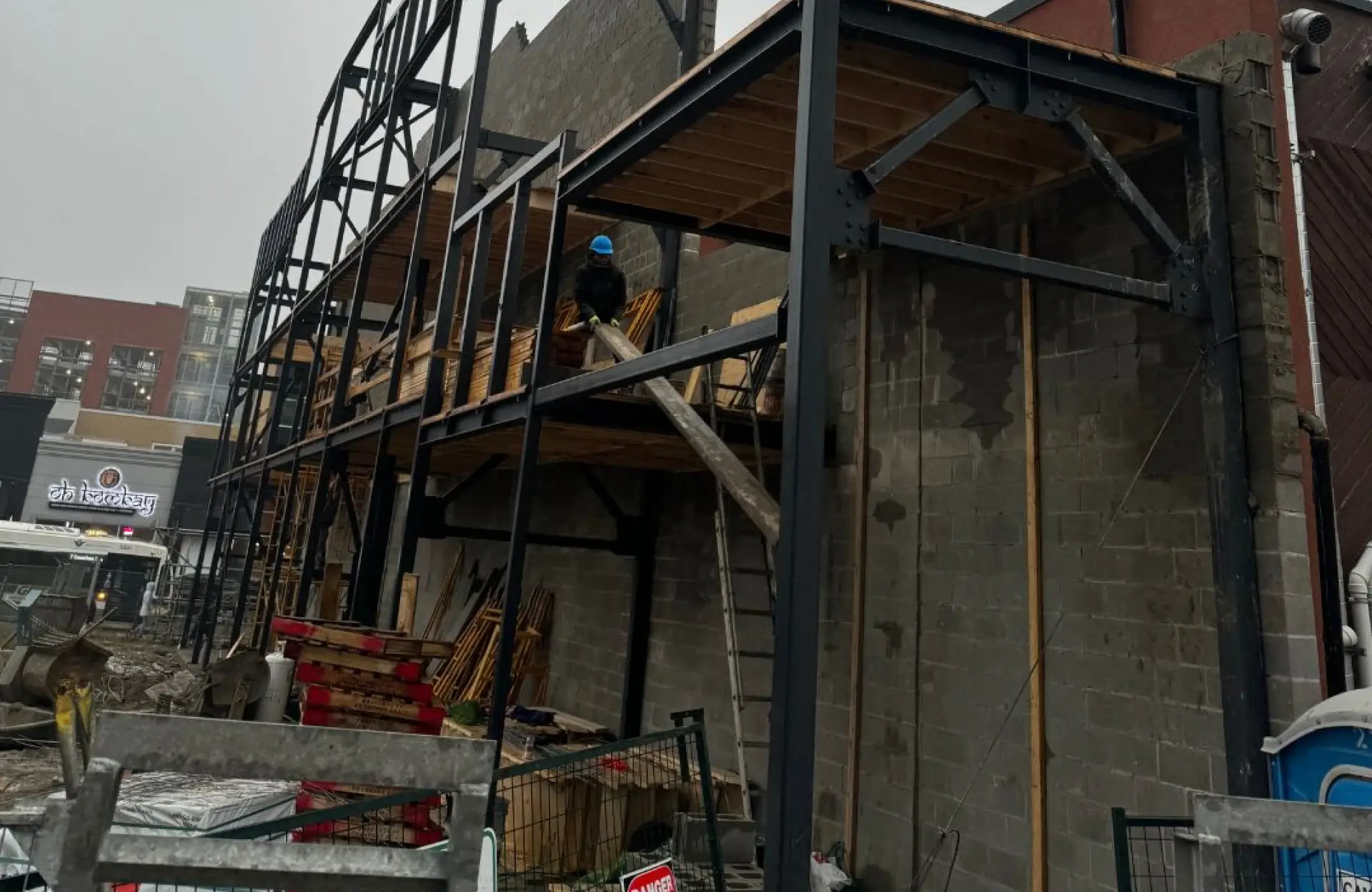 Stone Haven Developments A construction worker stands on the first floor of a partially built structure made of steel beams and concrete blocks, surrounded by building materials and debris. Ontario