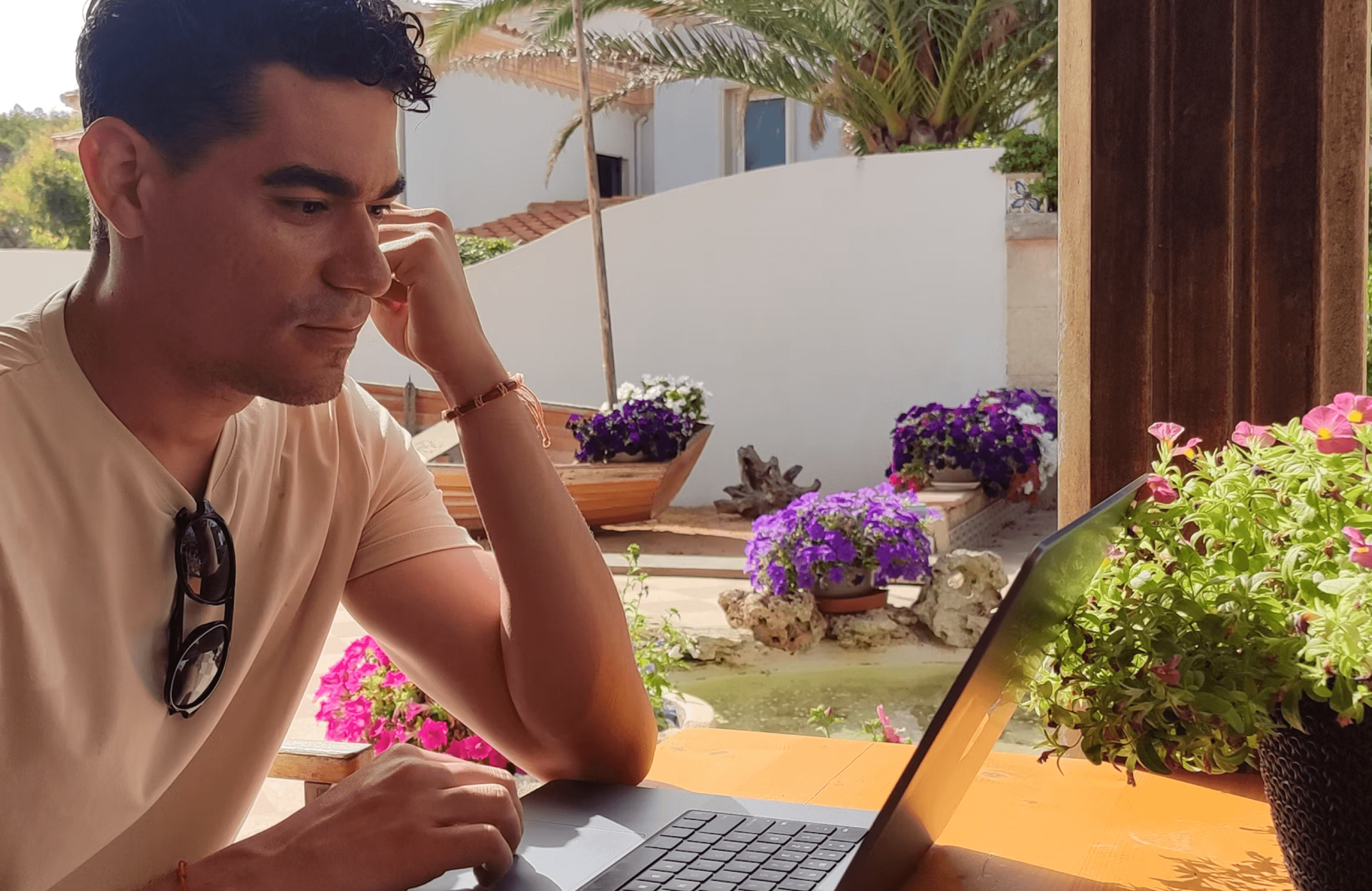 Stone Haven Developments A man sits at an outdoor table working on a laptop, surrounded by potted flowers and plants in a sunny garden setting. Ontario