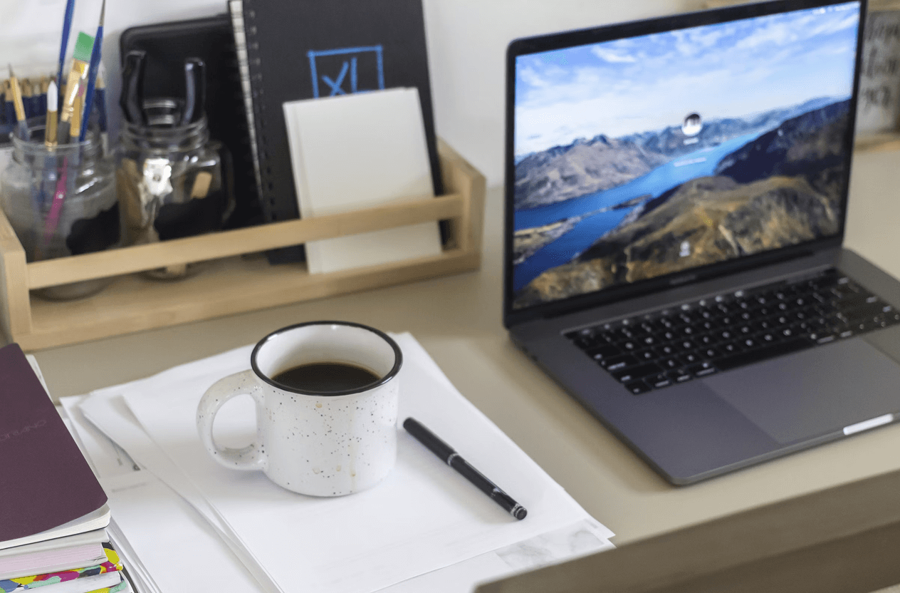 Stone Haven Developments A coffee mug, pen, and papers sit on a desk next to an open laptop displaying a landscape image, with notebooks and jars of pens in the background. Ontario