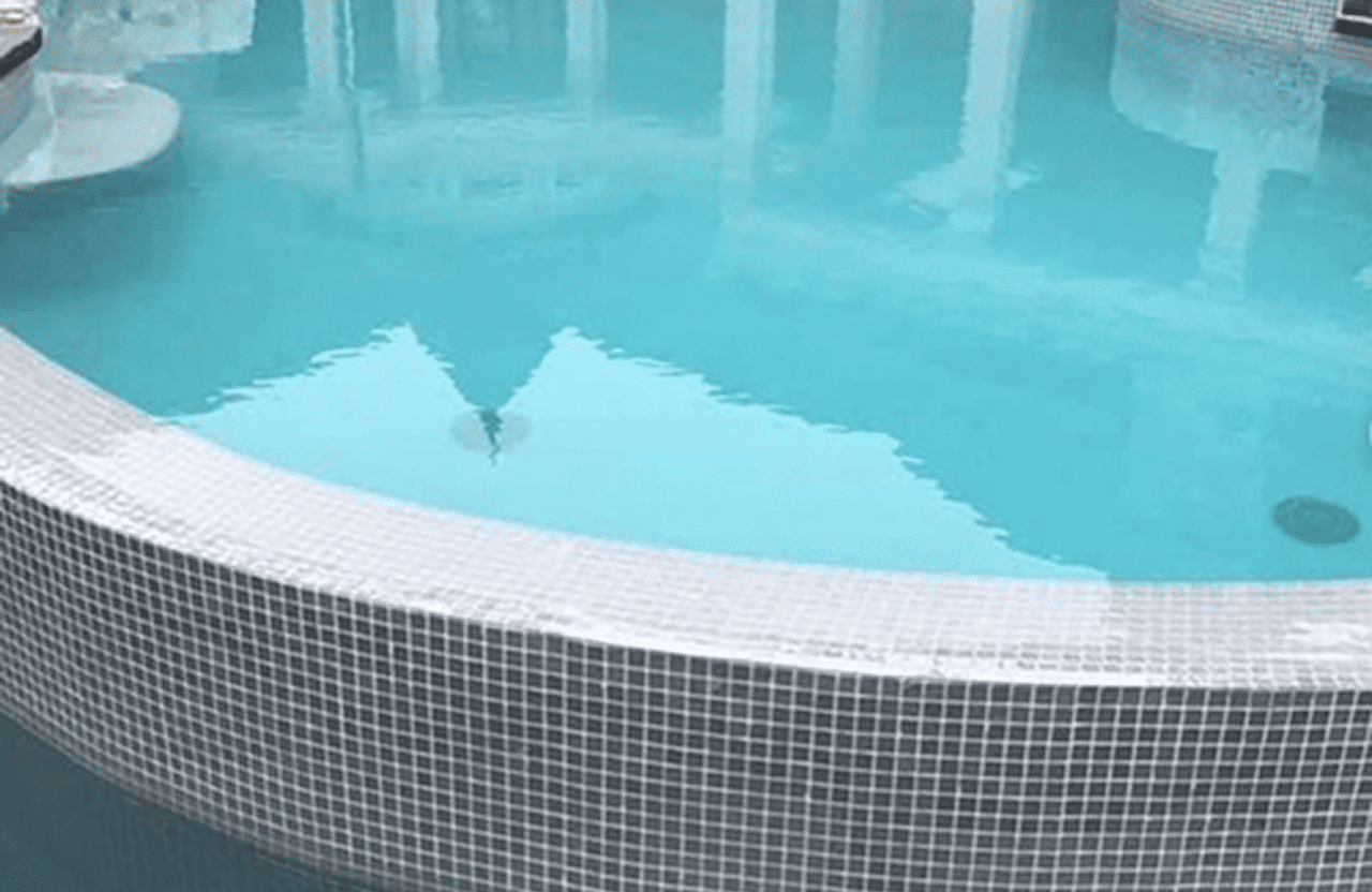 Stone Haven Developments Curved edge of a swimming pool with light blue water and small square white tiles along the pool's border. Ontario