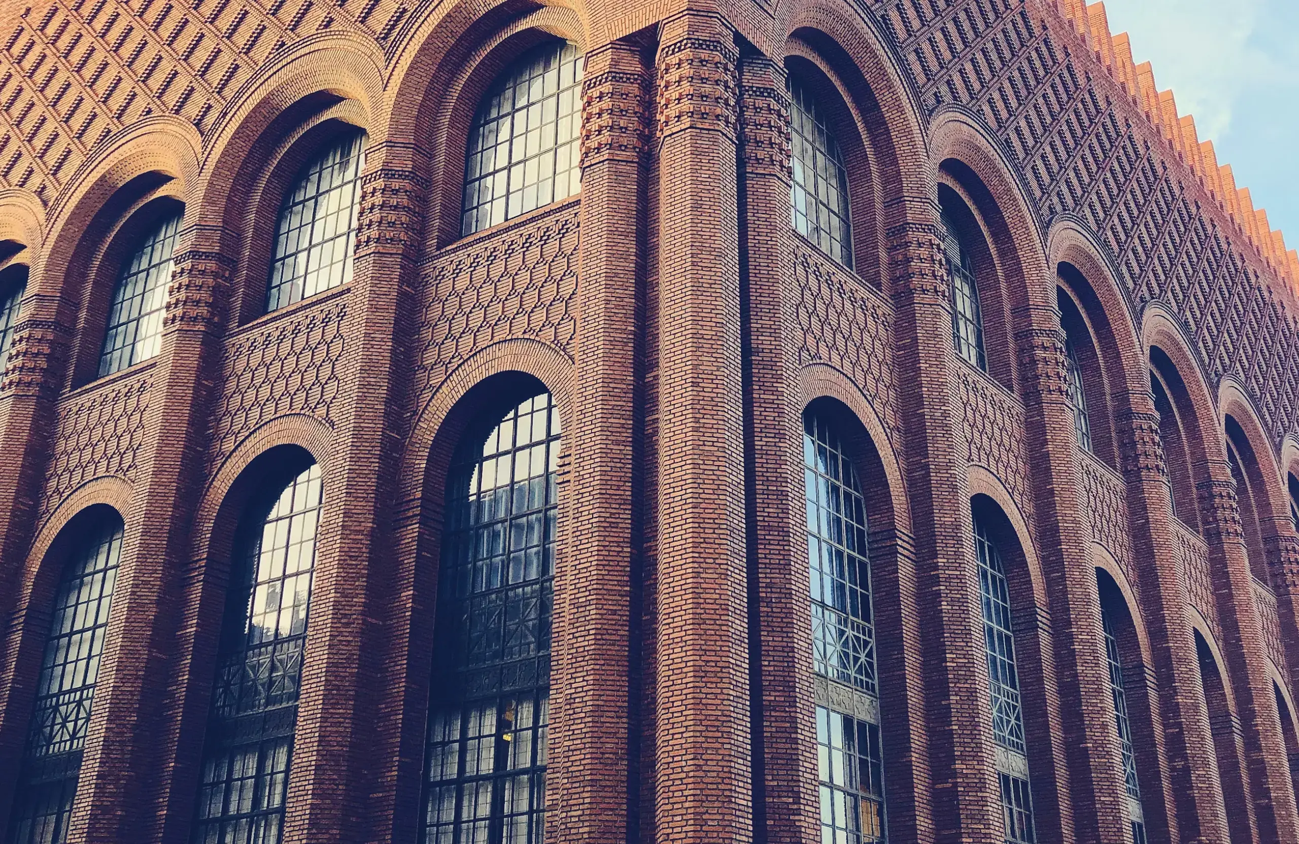Stone Haven Developments A brick building with large arched windows and decorative patterns on its facade, viewed from a low angle against a partly cloudy sky. Ontario