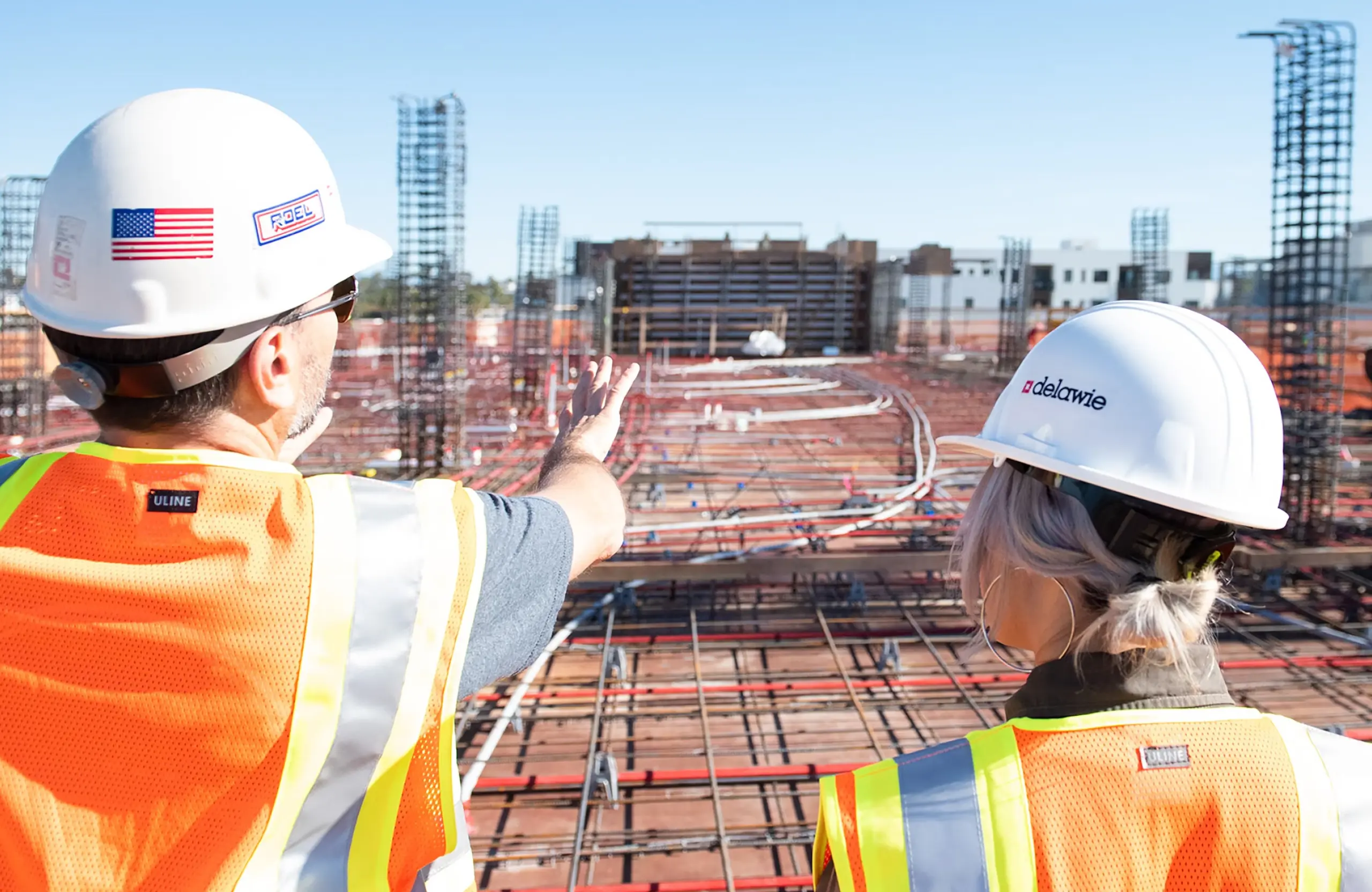 Stone Haven Developments Two construction workers wearing hard hats and safety vests stand on a building site, with one pointing towards the active construction area ahead. Ontario