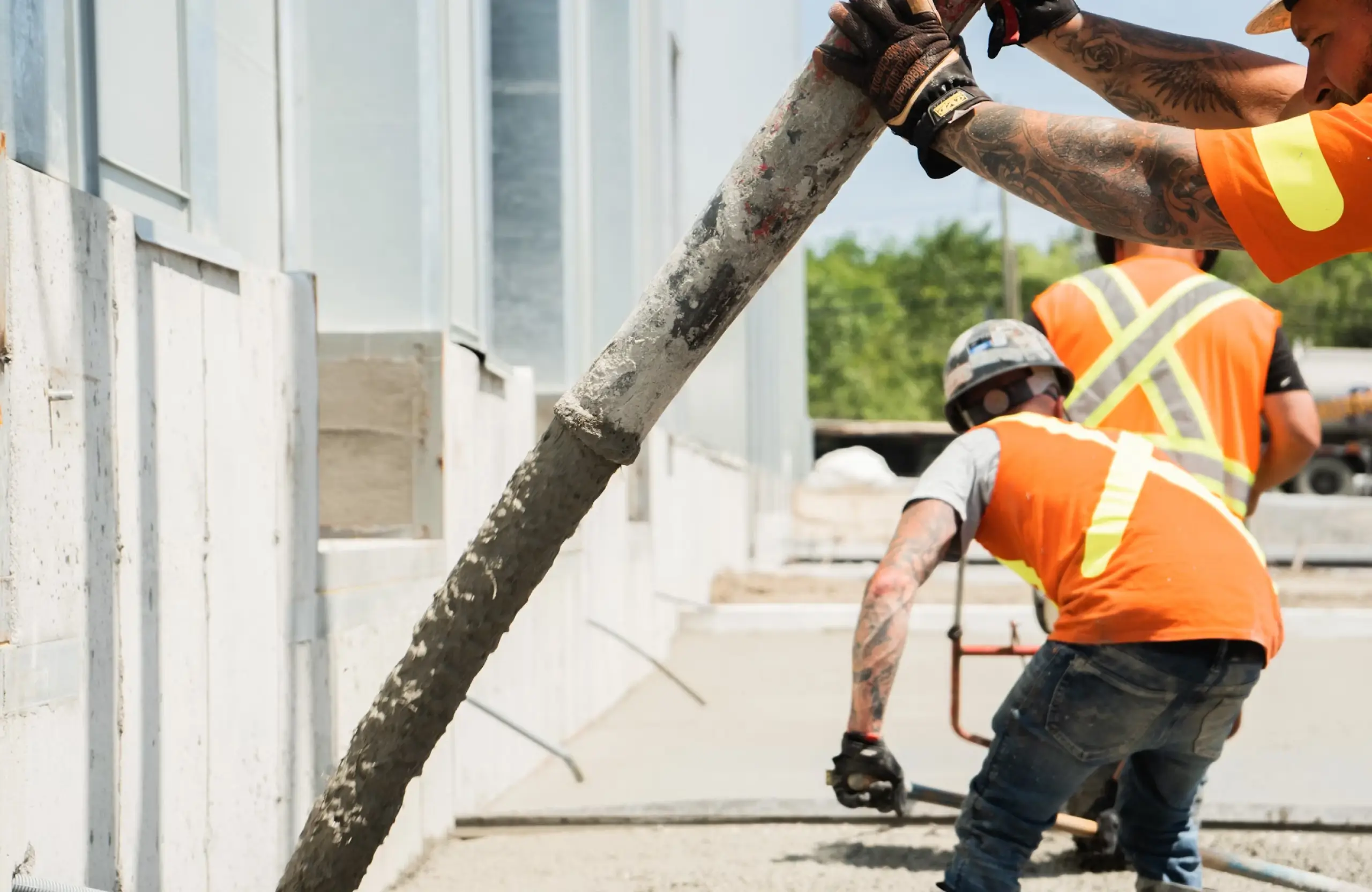 Stone Haven Developments Construction workers wearing safety gear pour concrete from a large hose onto the ground at a building site. Ontario