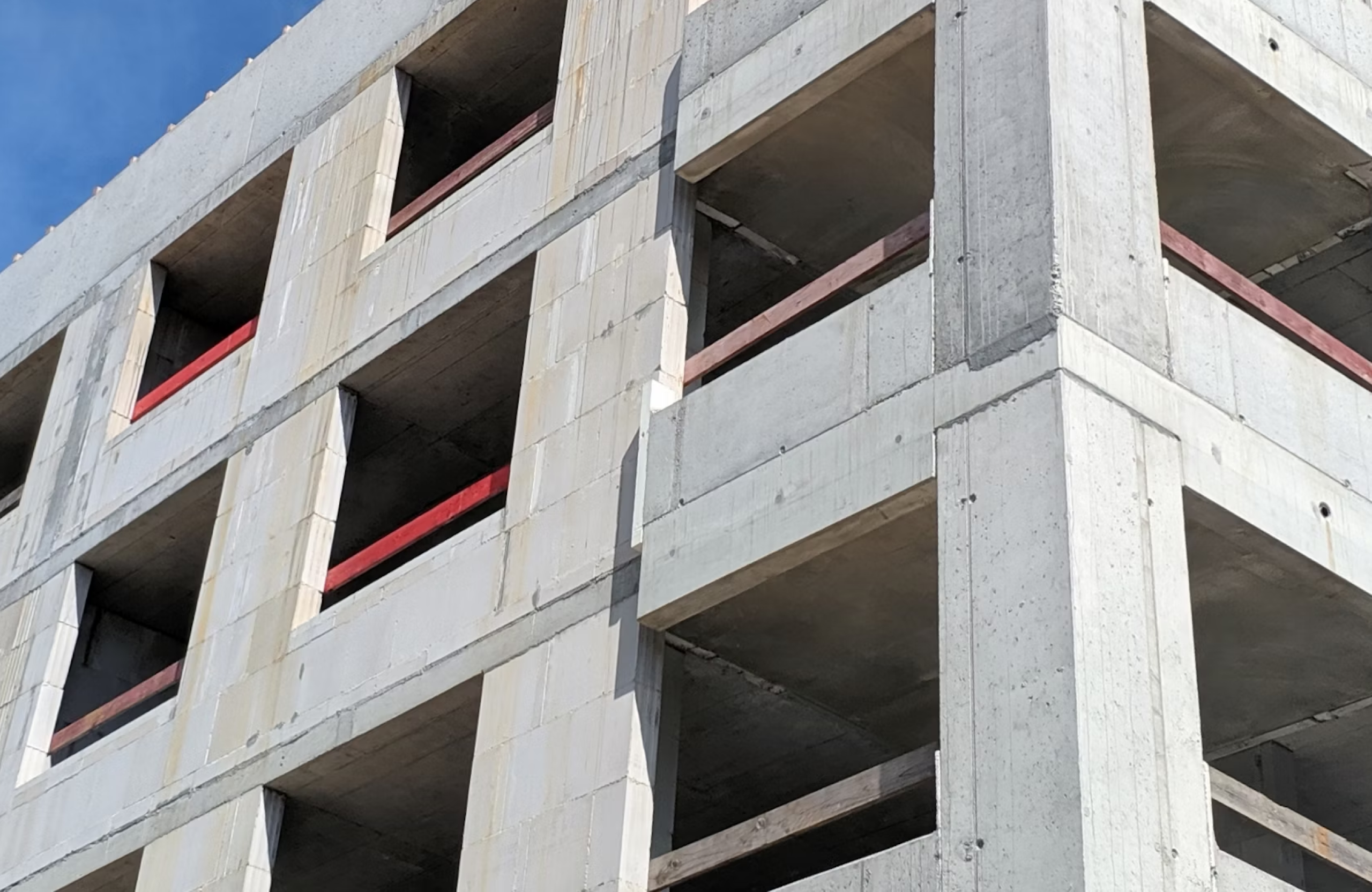 Stone Haven Developments A partially constructed concrete building with open rectangular window spaces and red railings, viewed from an upward angle. Ontario