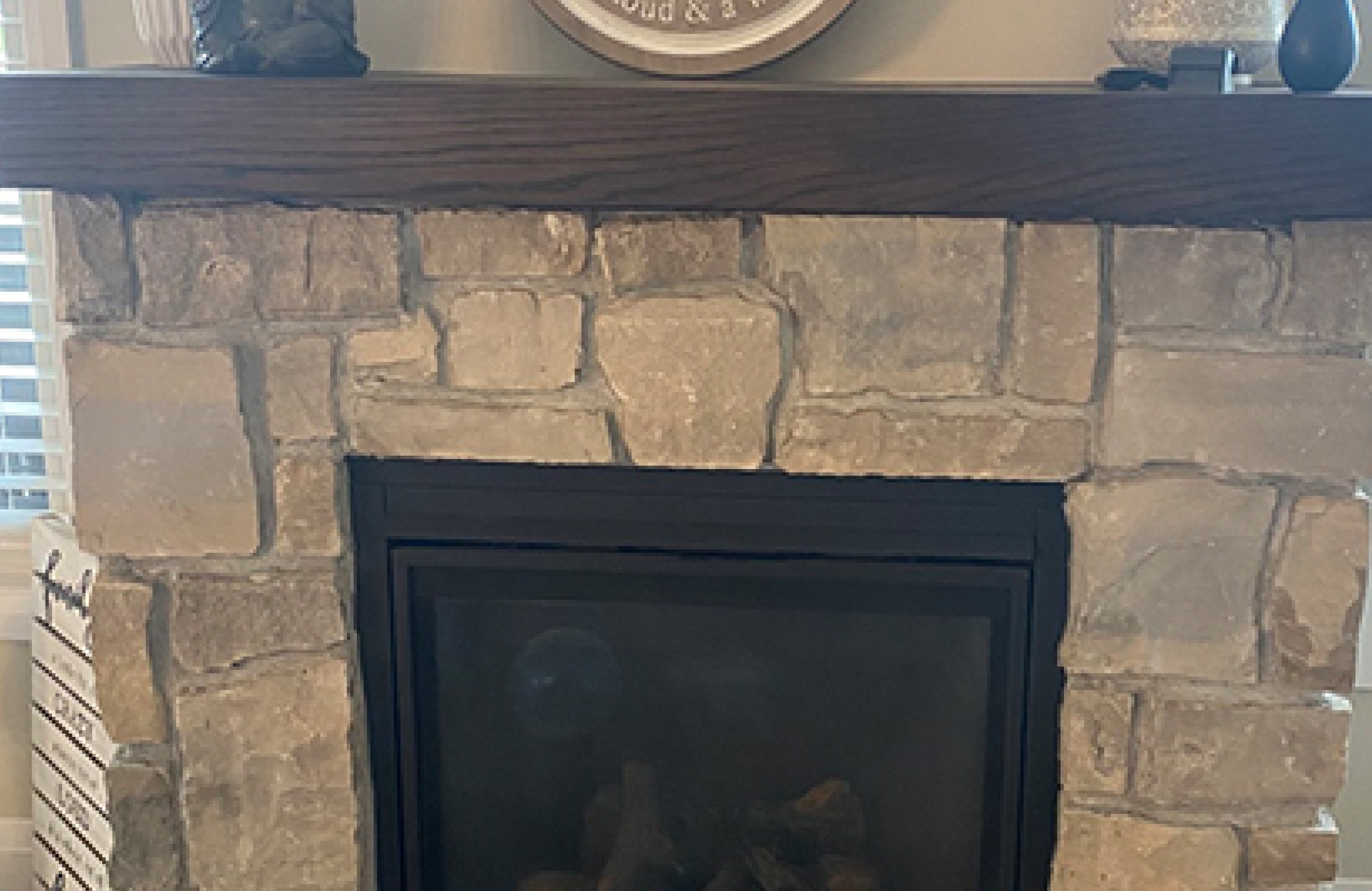 Stone Haven Developments A stone fireplace with a dark wooden mantel displays small decorative items and a round sign above it. Ontario