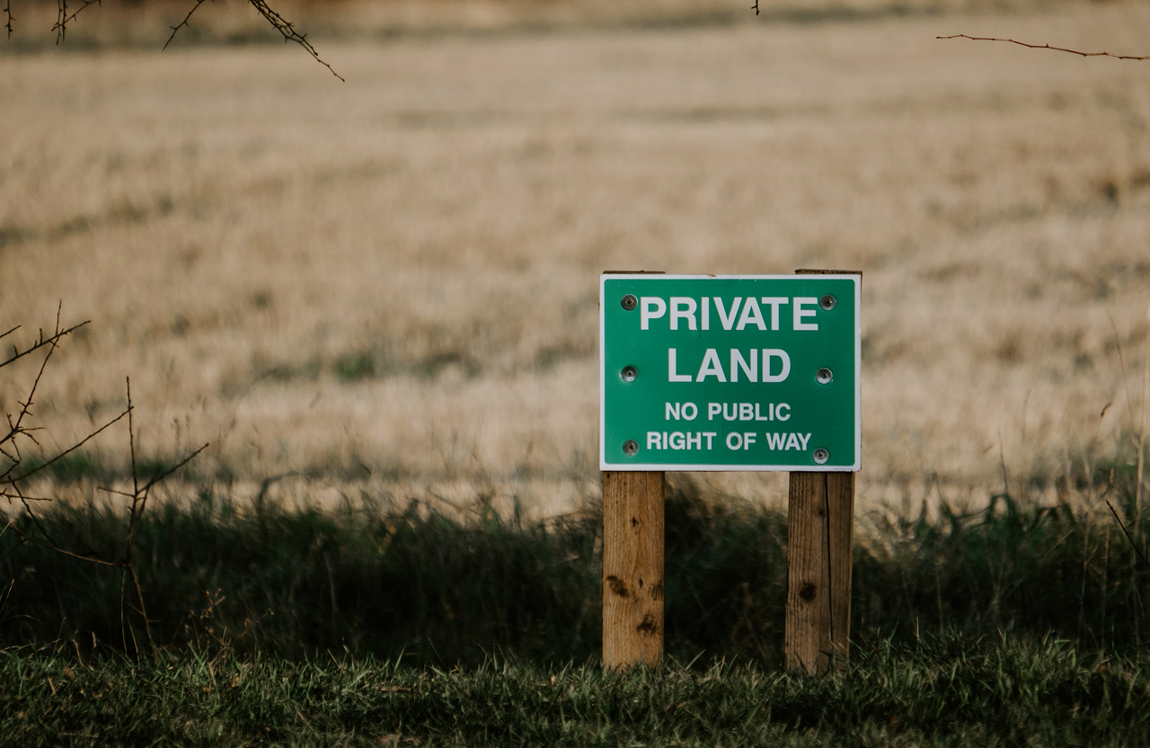 Stone Haven Developments A green and white sign on wooden posts reads "Private Land, No Public Right of Way" in front of a grassy field. Ontario