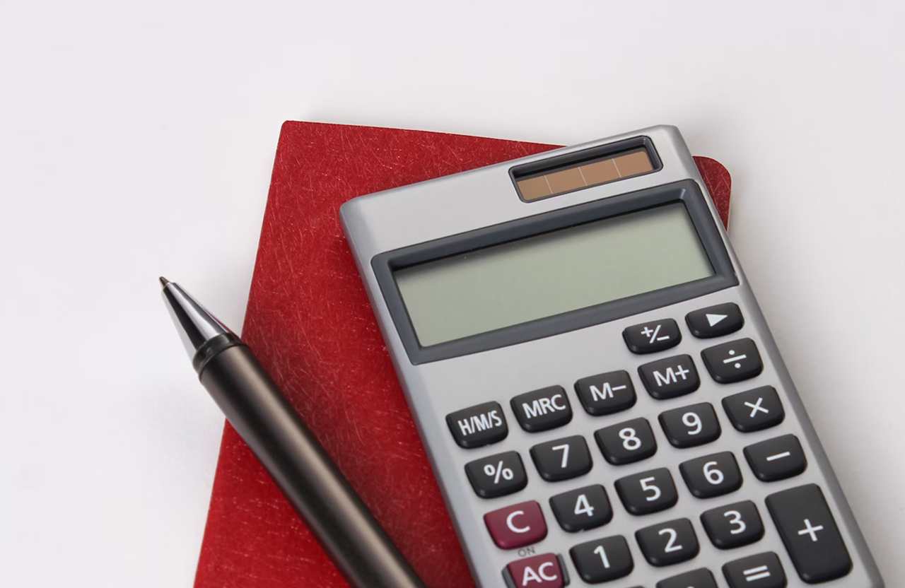 Stone Haven Developments A calculator, a closed red notebook, and a black pen are arranged on a white surface. Ontario