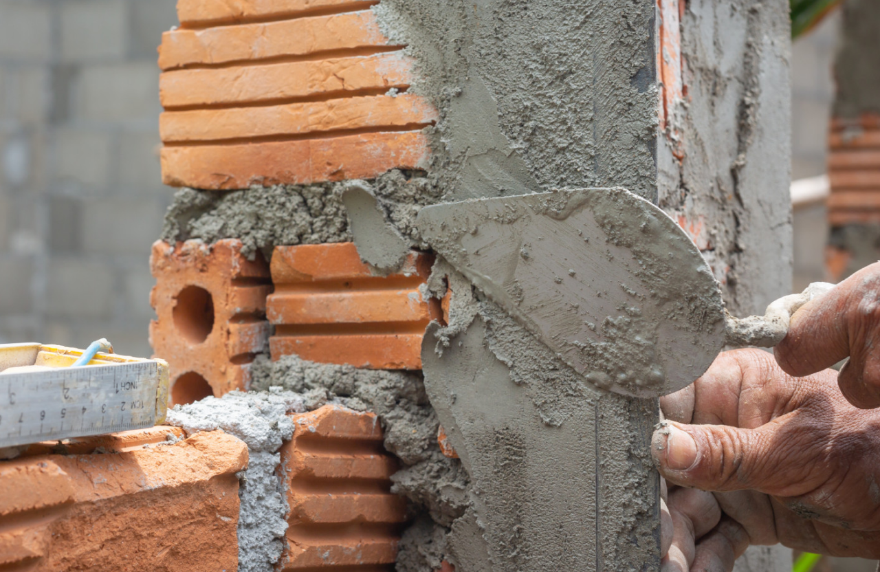 Stone Haven Developments A close-up of a person applying mortar to brickwork with a trowel during wall construction. Ontario