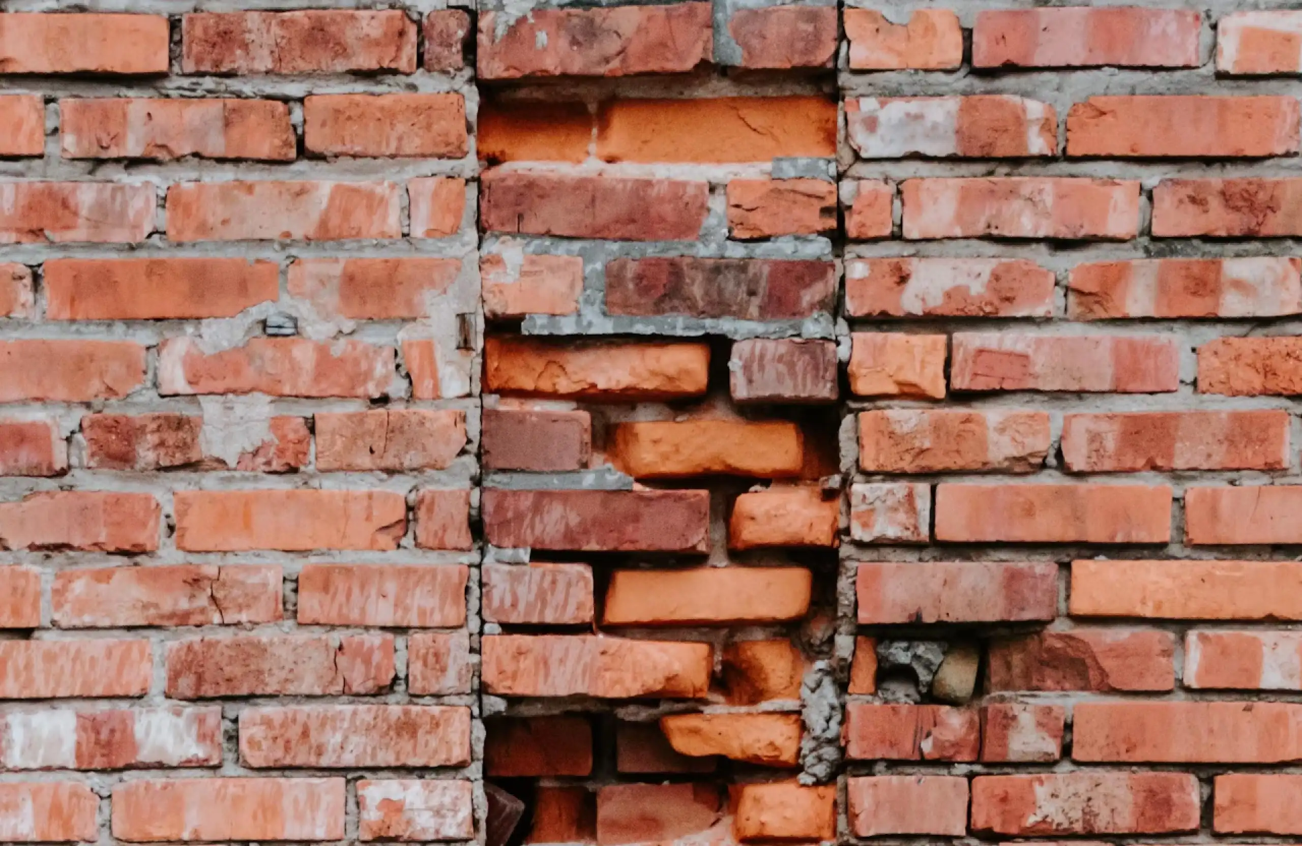 Stone Haven Developments A brick wall with a vertical section in the center where the bricks are uneven, misaligned, and appear damaged. Ontario