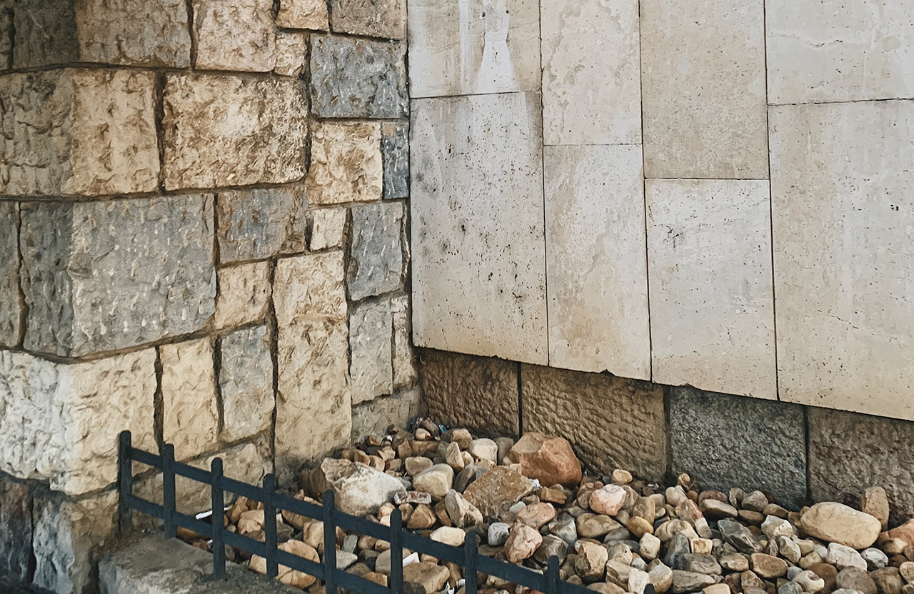 Stone Haven Developments A small iron fence borders a bed of assorted rocks in front of a stone wall and a concrete wall. Ontario
