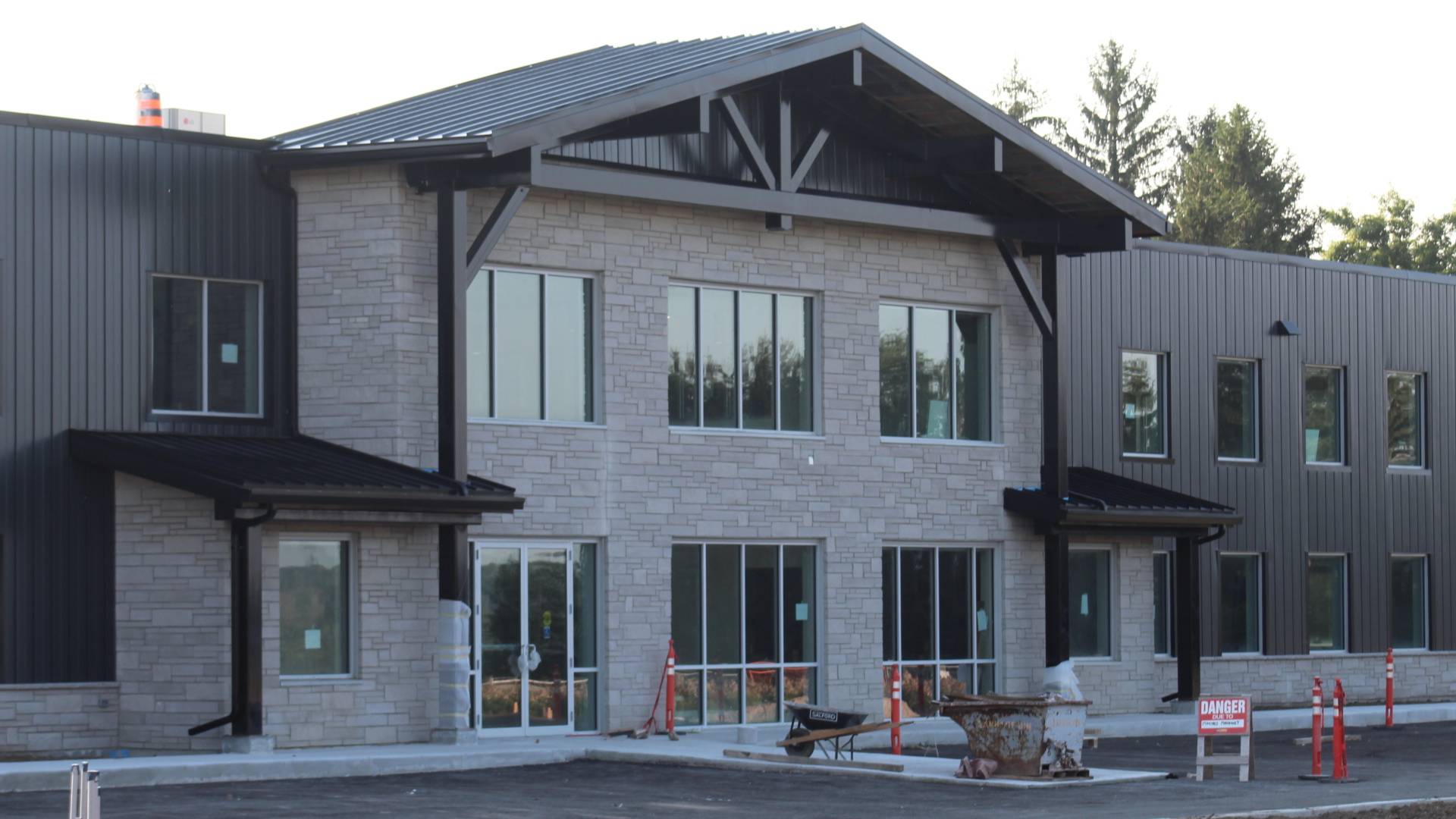 Stone Haven Developments Two-story commercial building with stone and metal exterior, large windows, and glass entrance; construction materials and barriers visible in front. Ontario
