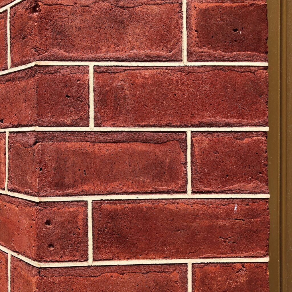Stone Haven Developments Close-up view of a red brick wall corner with beige mortar and a vertical brown trim on the right side. Ontario